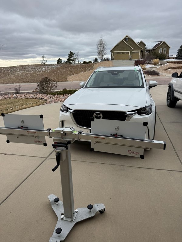 ADAS calibration target board positioned in front of a white SUV in Colorado Springs