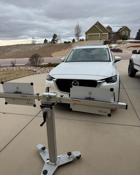ADAS calibration target board positioned in front of a white SUV in Colorado Springs