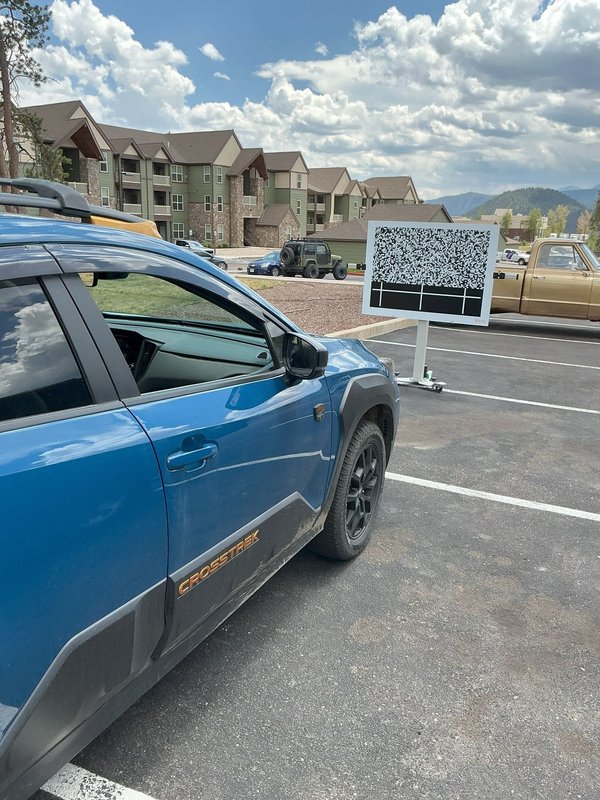 Blue crossover beside an ADAS calibration target board in Colorado Springs