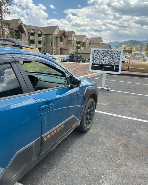 Blue crossover beside an ADAS calibration target board in Colorado Springs