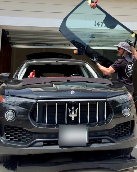 Shattered Vision Master Technician lifting a new windshield into place on a black Maserati SUV in Colorado Springs
