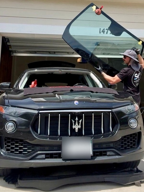 Shattered Vision Master Technician lifting a new windshield into place on a black Maserati SUV in Colorado Springs