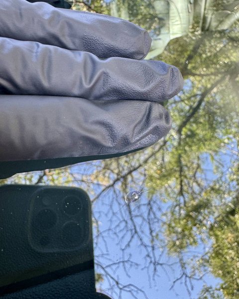 Shattered Vision technician inspecting a windshield against the sky, Colorado Springs
