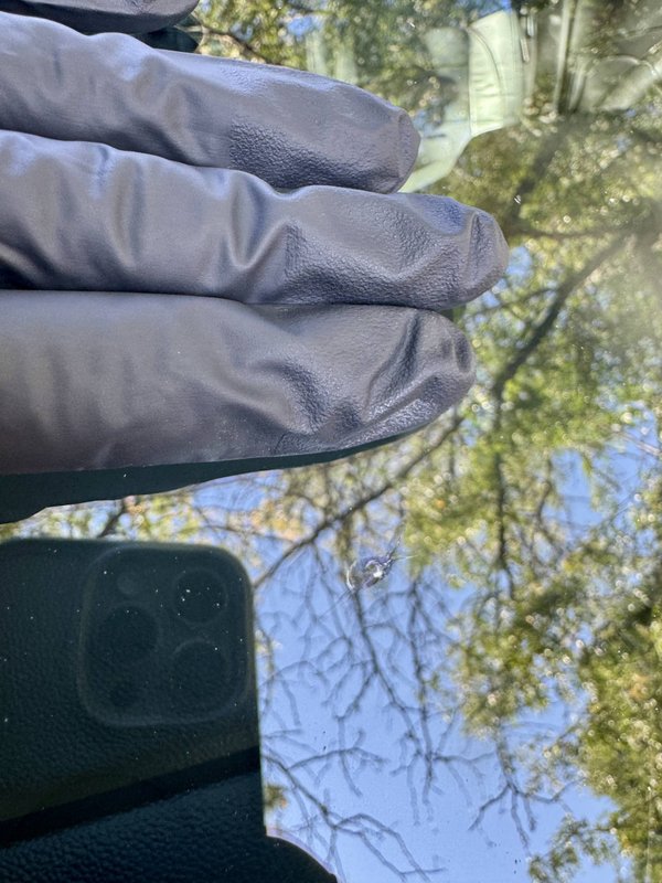 Shattered Vision technician inspecting a windshield against the sky, Colorado Springs